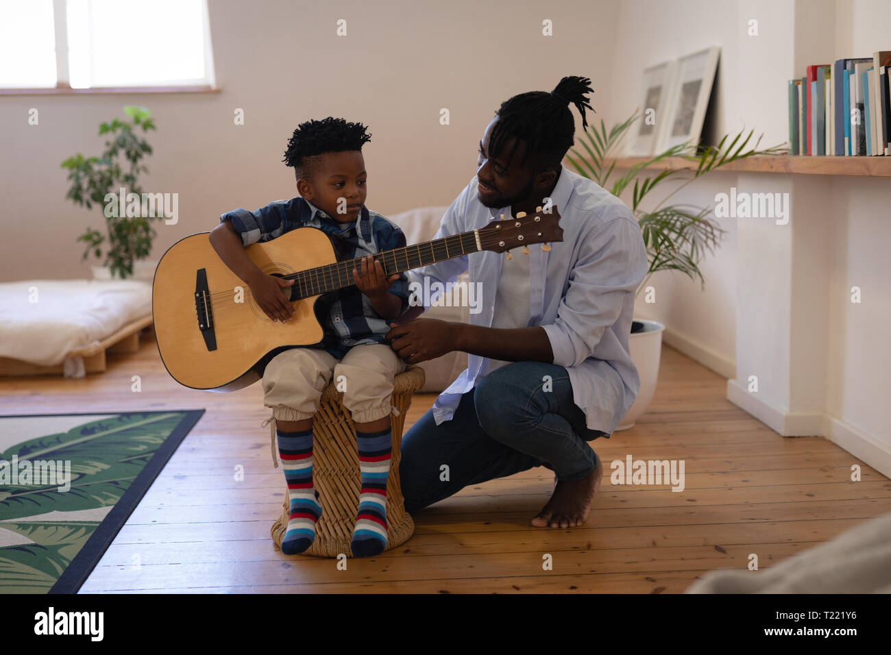 Father assisting his son to play guitar at home Stock Photo