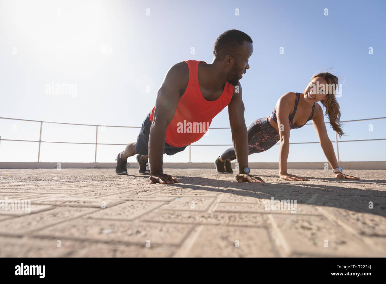 Couple interacting with each other while doing push ups on pavement Stock Photo