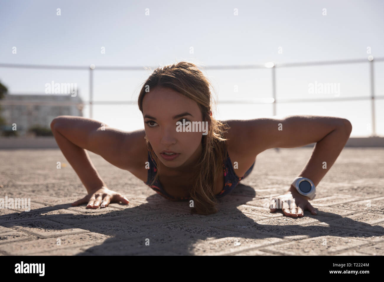 Beautiful woman doing push ups on pavement near beach Stock Photo