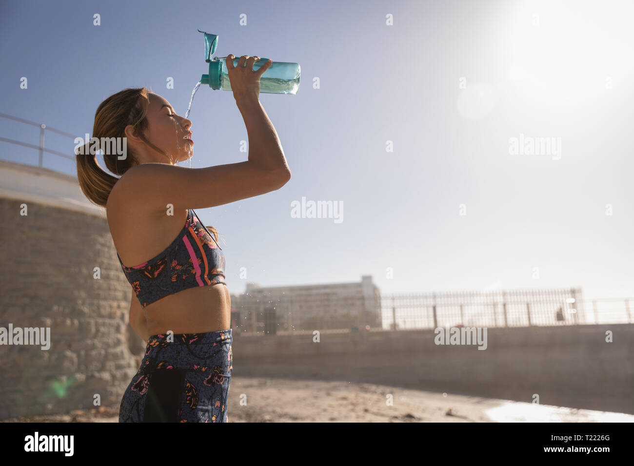 Woman pouring water on her face after workout exercise at beach Stock Photo