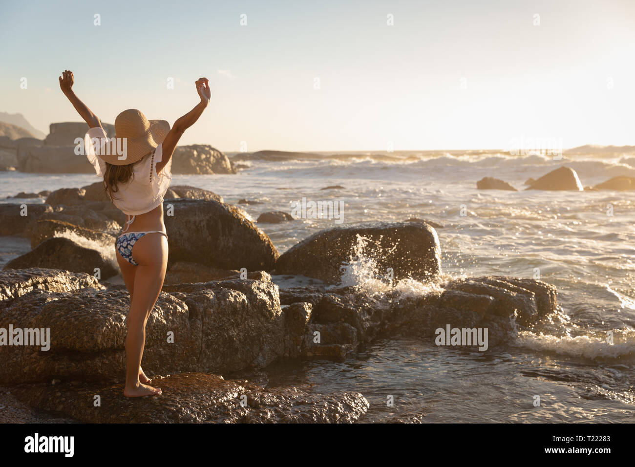 Beautiful woman standing with open arm at beach on a sunny day Stock Photo