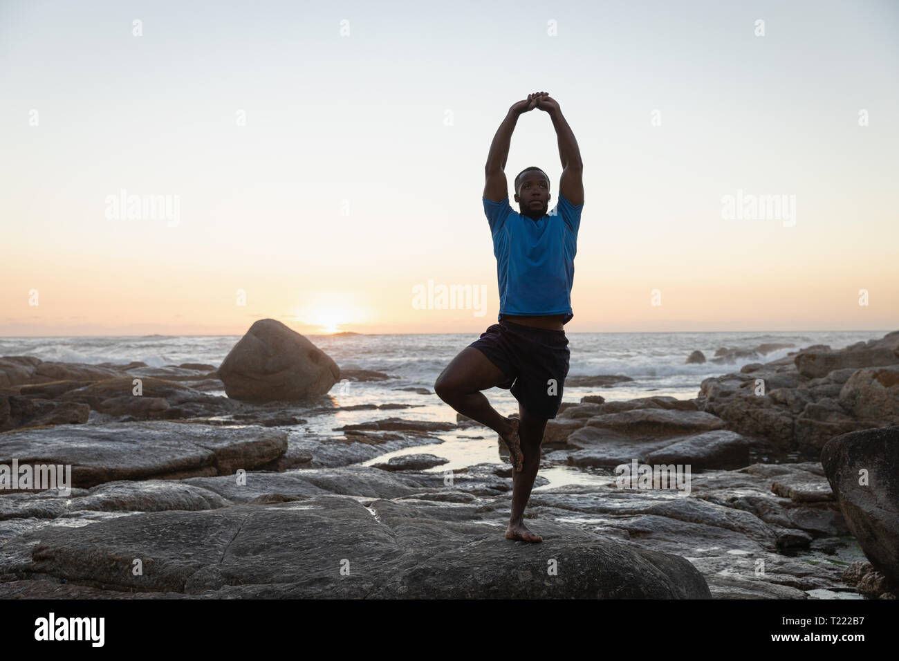 Man doing yoga at beach Stock Photo