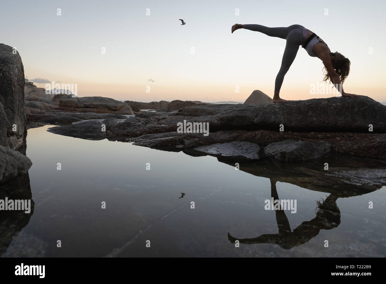 Woman doing yoga on rock at beach Stock Photo