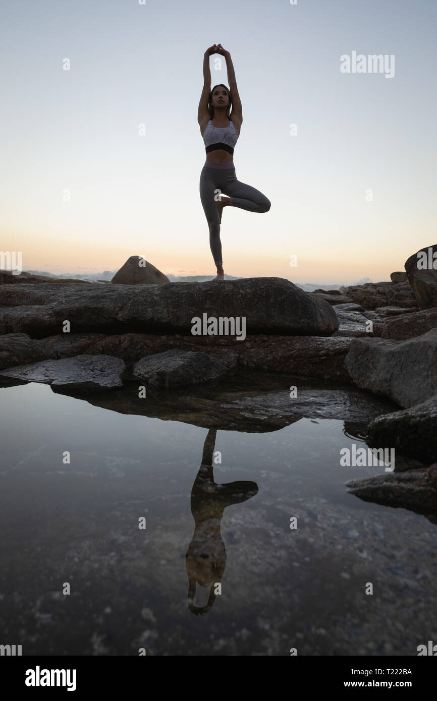 Woman doing yoga on rock at beach Stock Photo