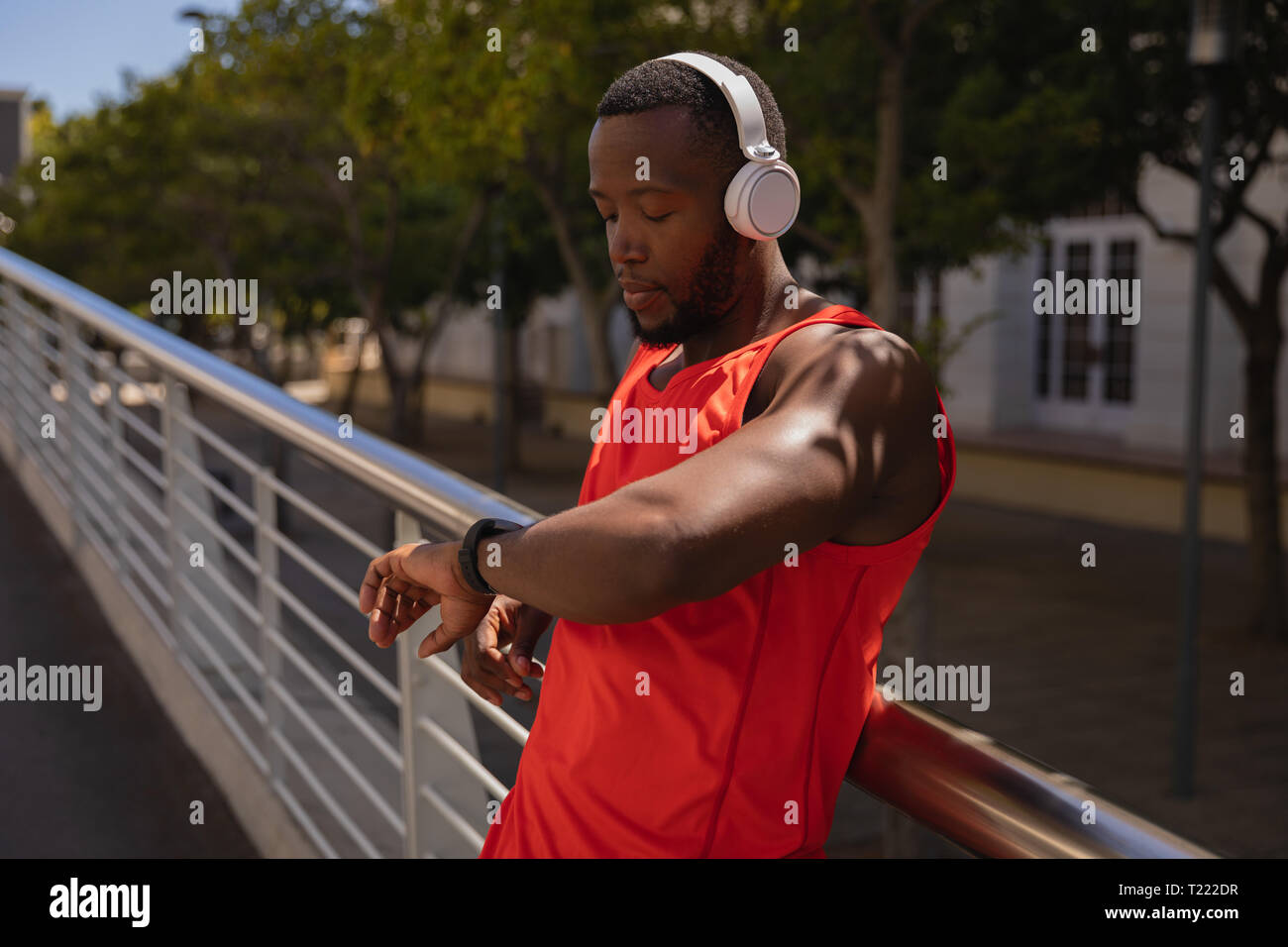 Man with headset looking at smart watch while standing by railing Stock Photo