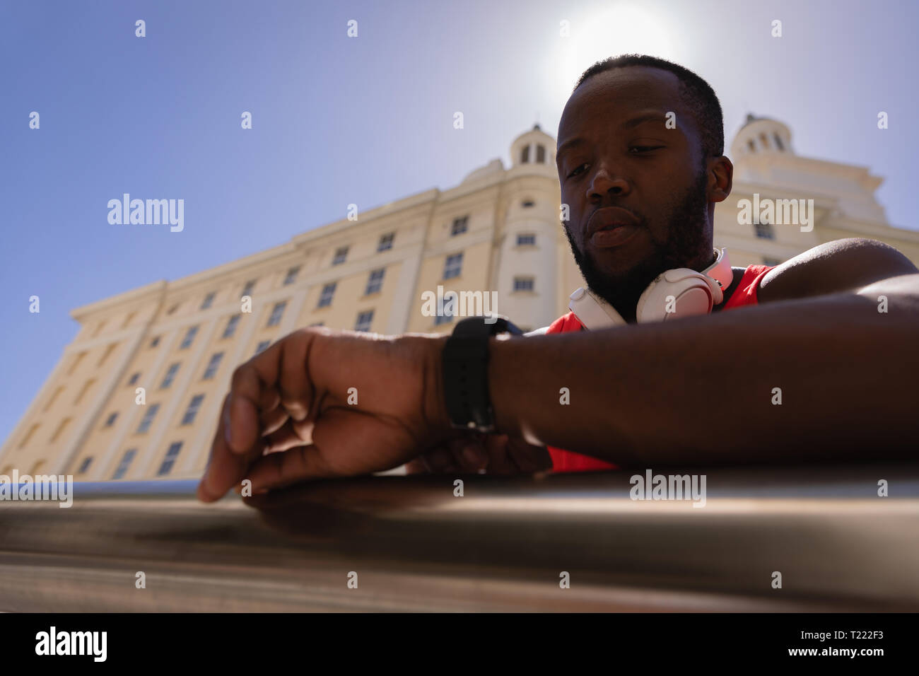 Man with headset looking at smart watch while standing by railing Stock Photo