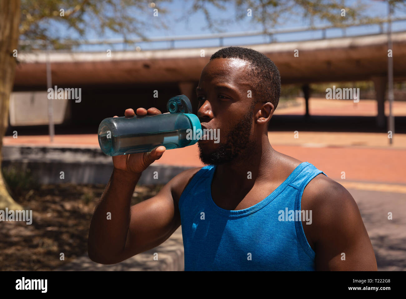 Man drinking water while standing on street on a sunny day Stock Photo