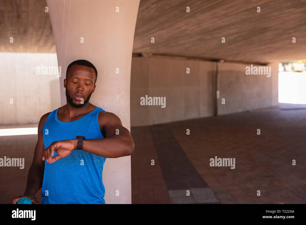 Man looking at smart watch while standing under the bridge Stock Photo