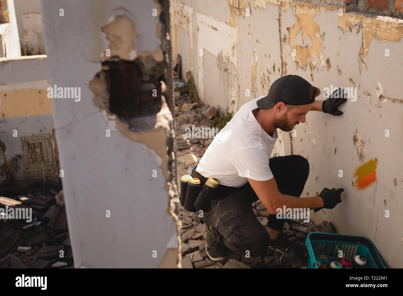 Graffiti artist spray painting wall at alley Stock Photo - Alamy