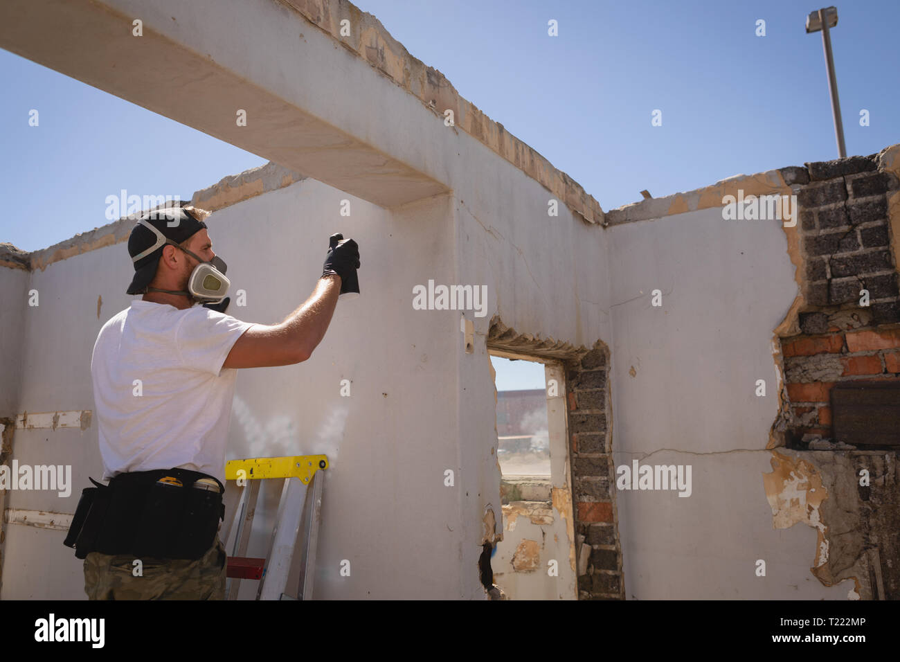 Graffiti artist spray painting weathered wall at alley Stock Photo - Alamy