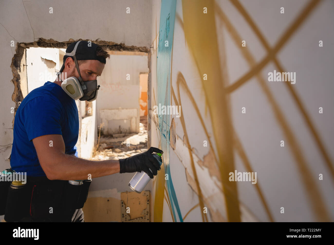 Graffiti artist spray painting weathered wall room Stock Photo - Alamy