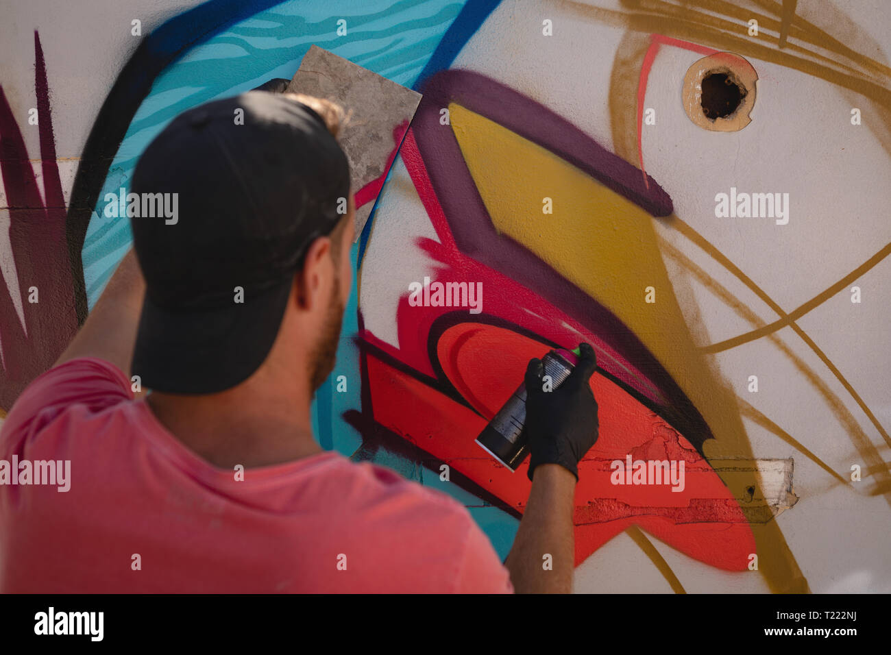 Graffiti artist spray painting on weathered wall room Stock Photo - Alamy