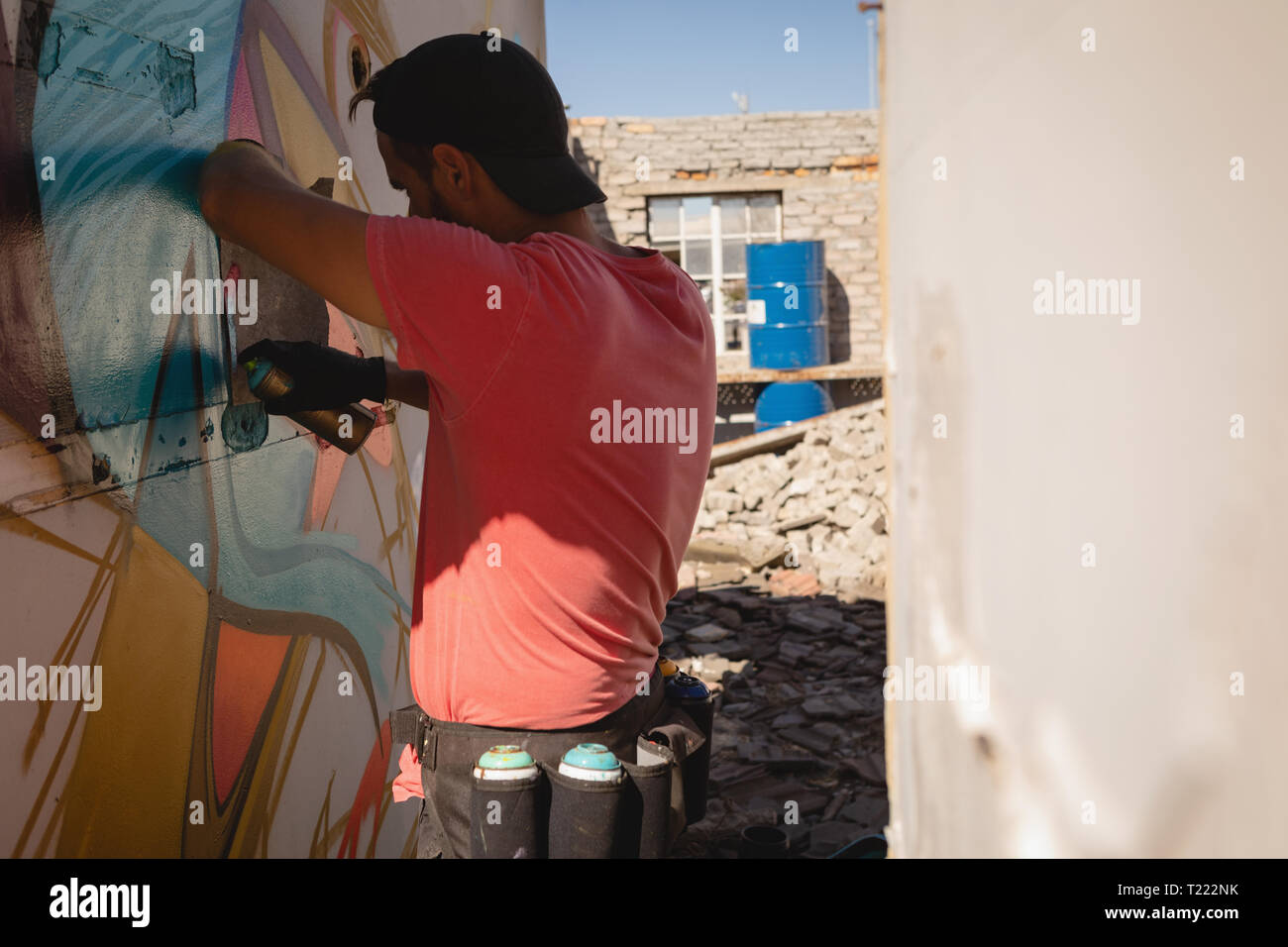 Graffiti artist spray painting on weathered wall room Stock Photo - Alamy