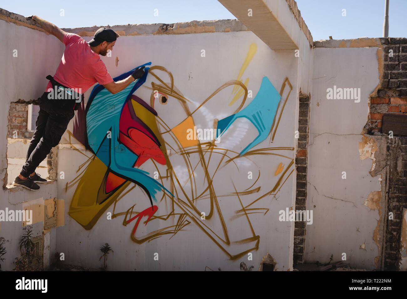 Graffiti artist spray painting on weathered wall Stock Photo Alamy