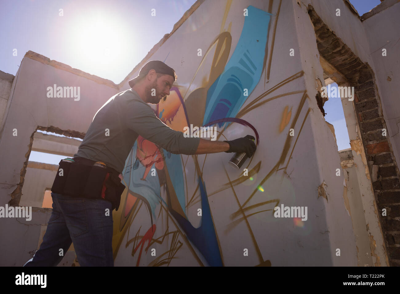 Graffiti artist spray painting on weathered wall room Stock Photo Alamy