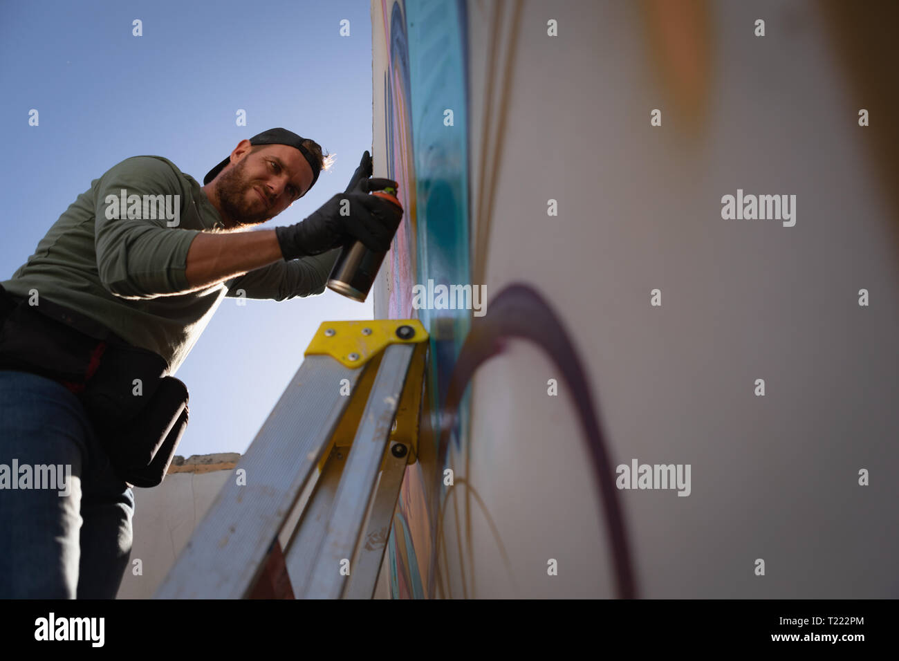 Graffiti artist spray painting on weathered wall room Stock Photo - Alamy