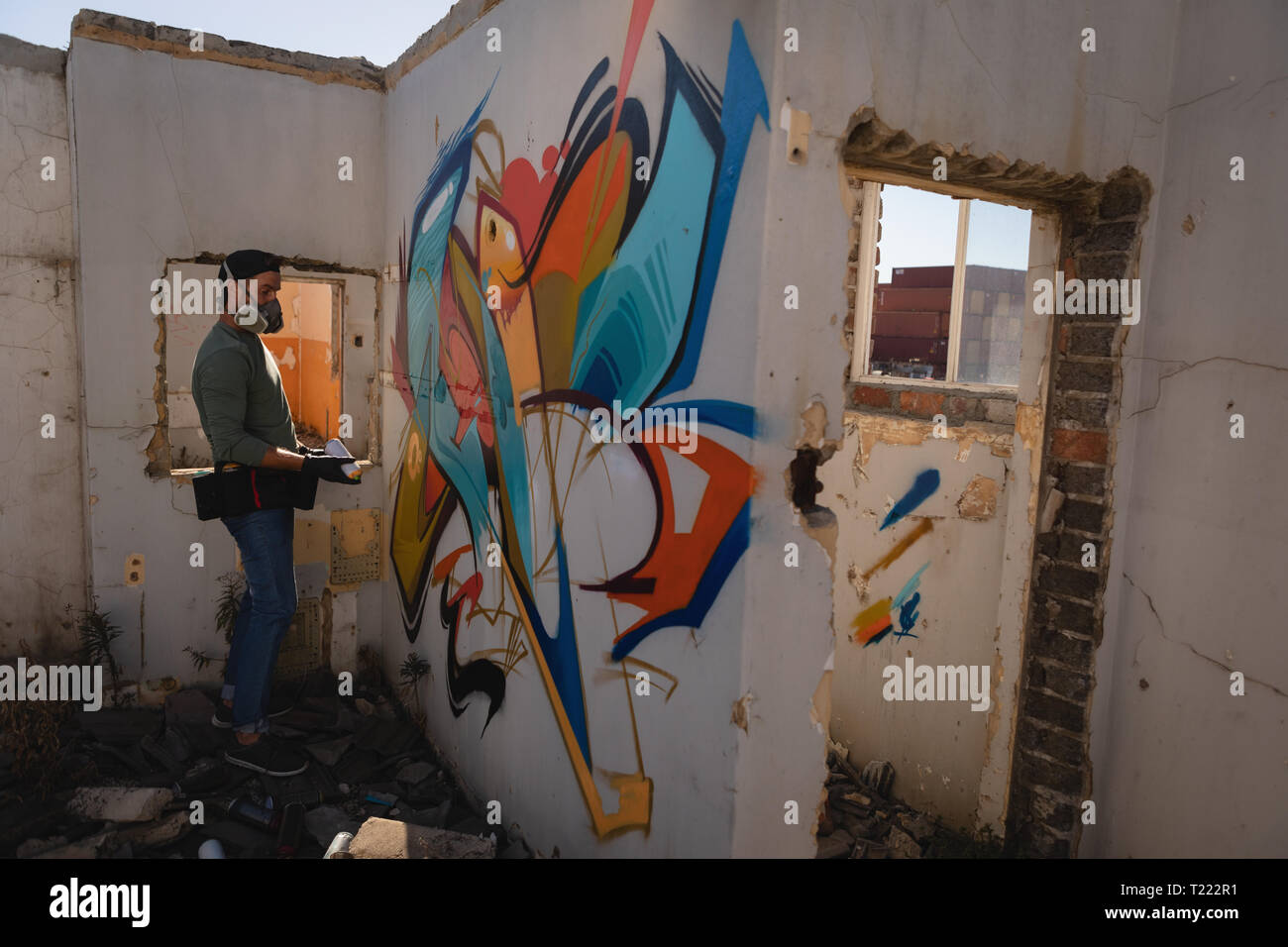 Graffiti artist spray painting on weathered wall Stock Photo - Alamy