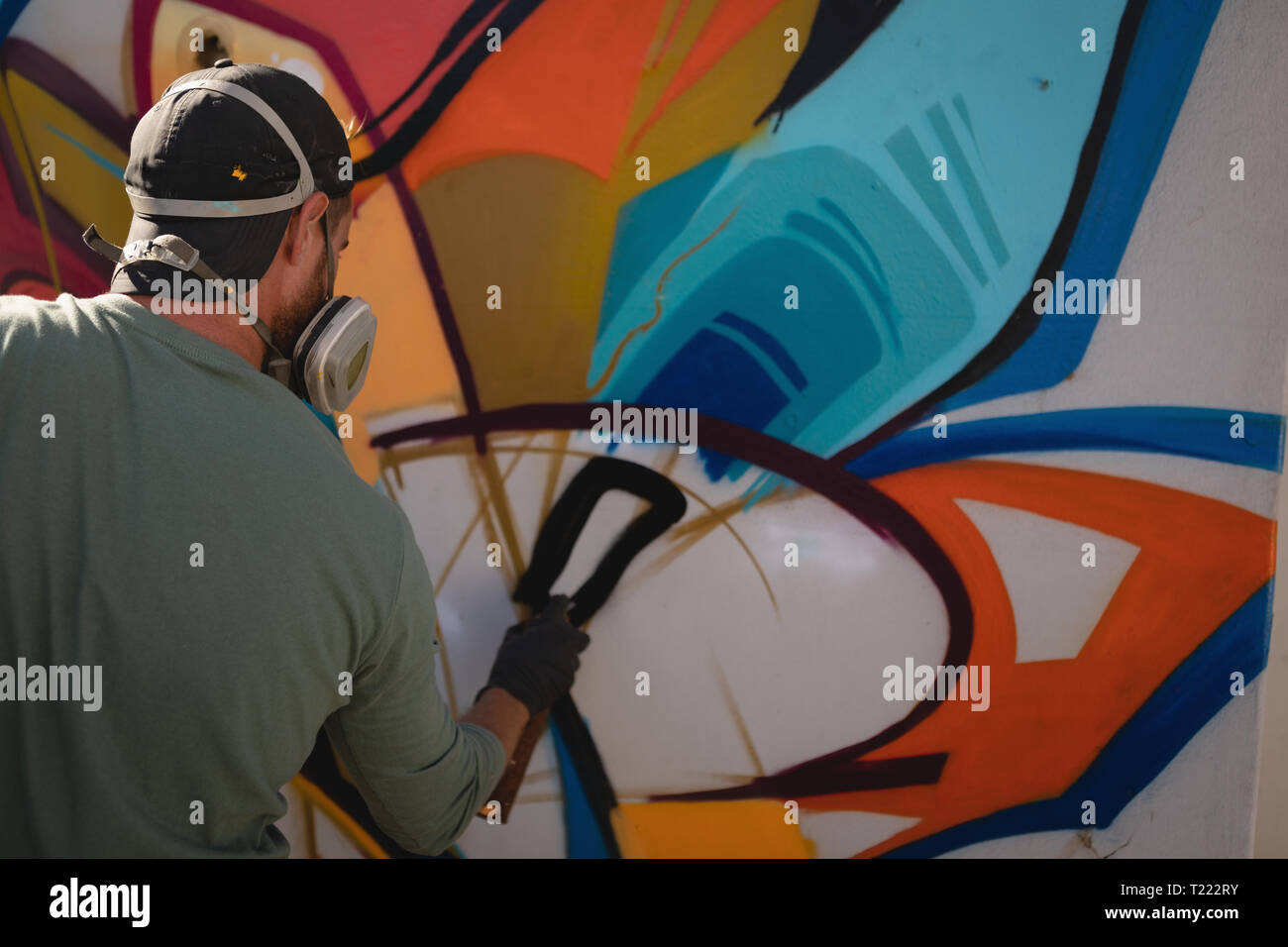 Graffiti artist spray painting on weathered wall Stock Photo - Alamy