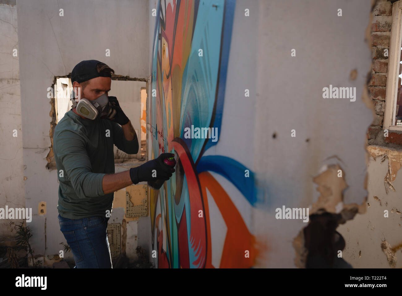 Graffiti artist spray painting on weathered wall Stock Photo - Alamy