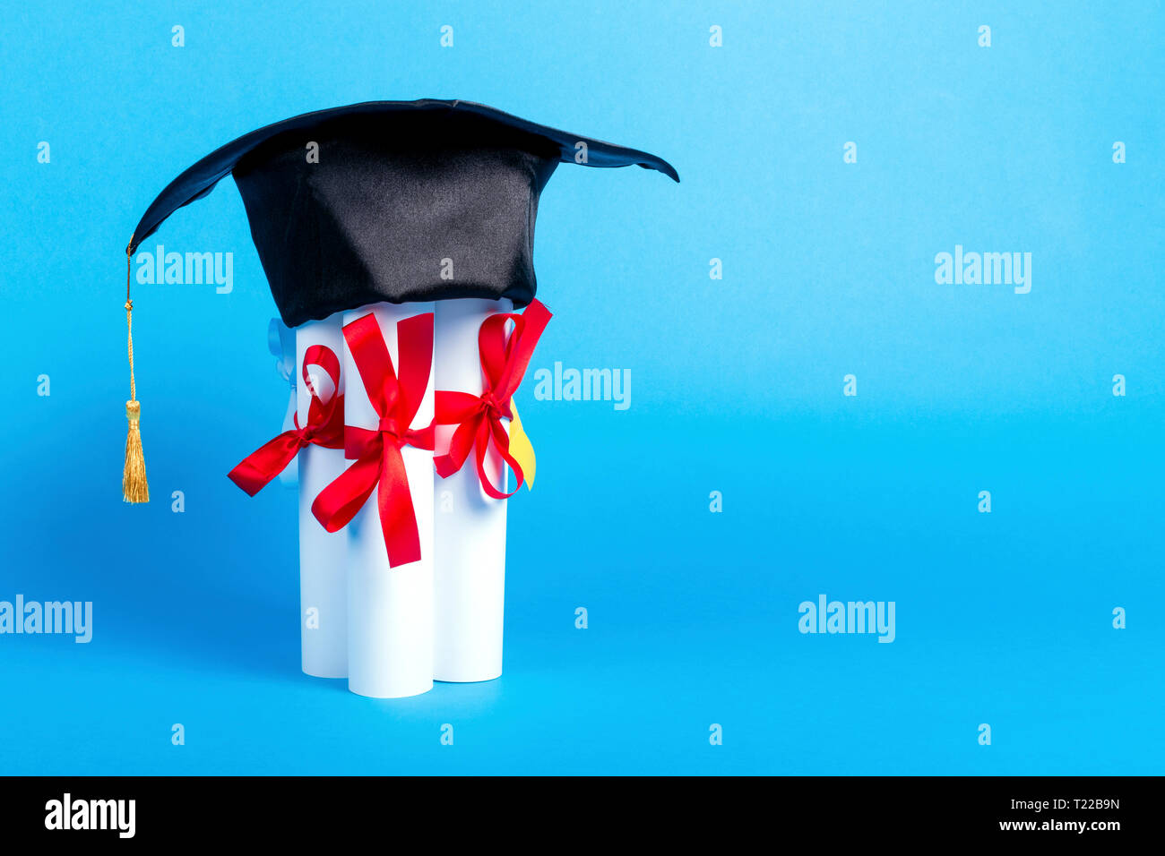 graduation cap on diplomas, image on blue background with copy space Stock Photo