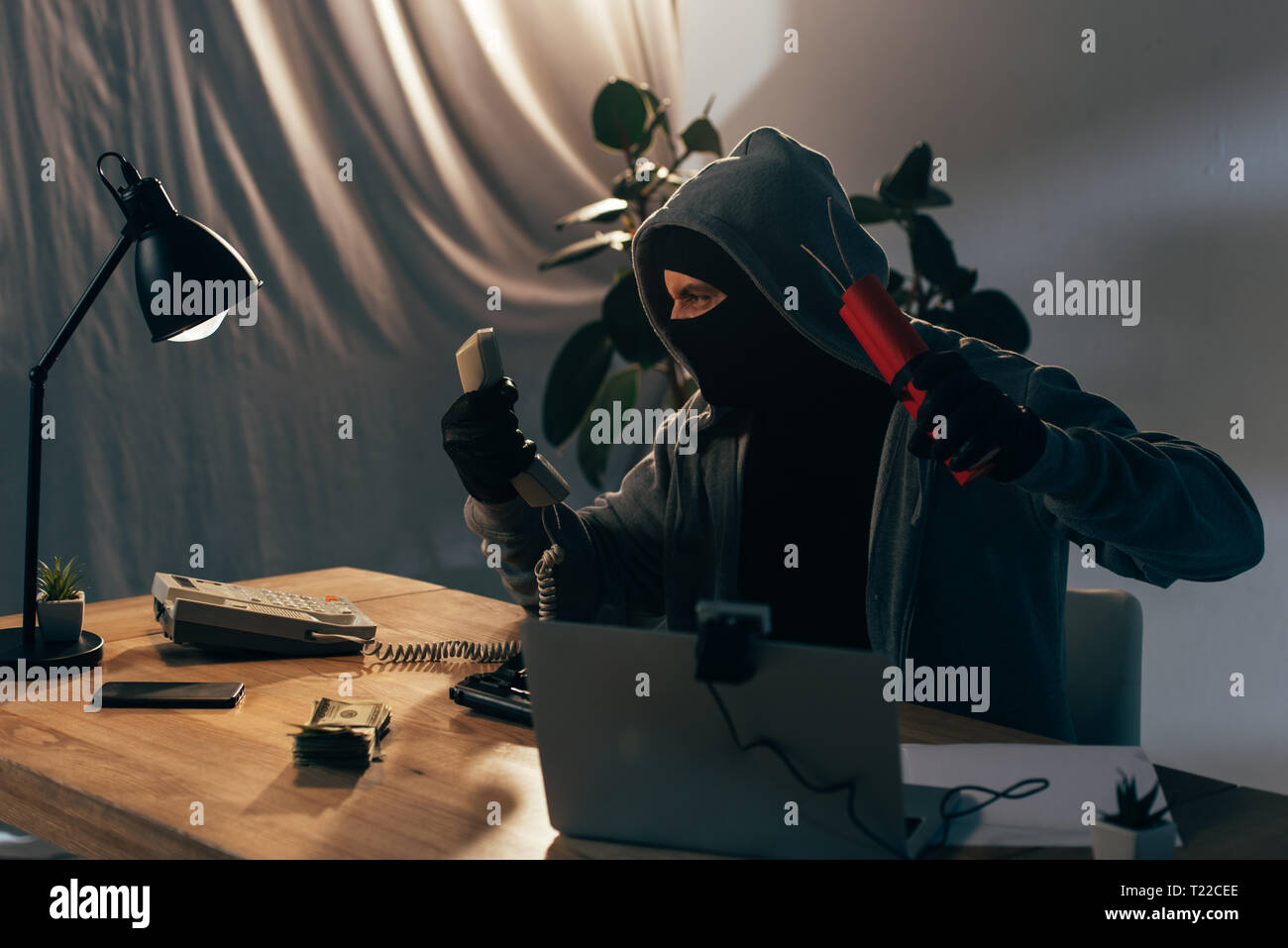 Angry Terrorist In Mask Sitting In Room And Holding Dynamite