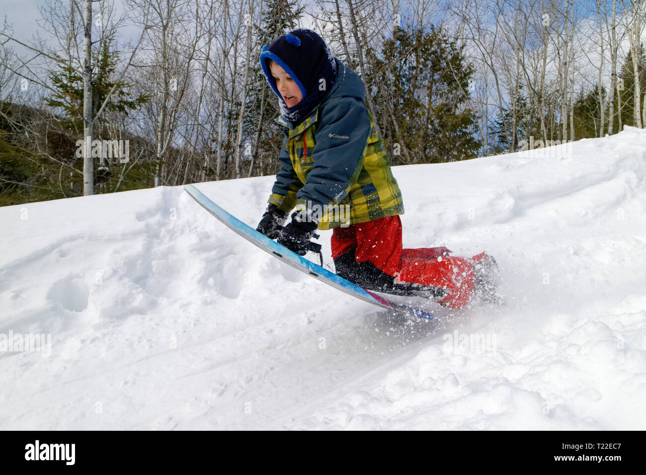 A little boy (6 yrs old) doing a jump on his sledge Stock Photo