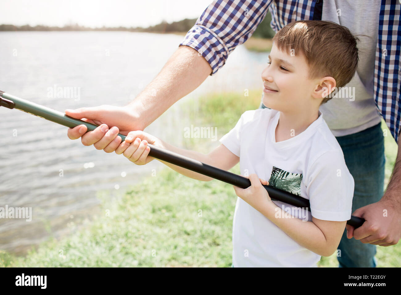 https://c8.alamy.com/comp/T22EGY/a-picture-of-guy-helping-his-son-to-hold-fish-rod-in-a-right-way-he-is-holding-it-with-one-hand-while-boy-is-doing-that-with-two-hands-small-man-see-T22EGY.jpg