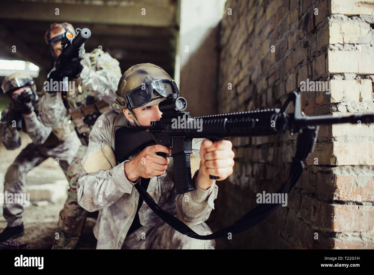 A picture of guy looking for an aim. He is loooking through loop gun. He is concentrated. There are two people with rifles standing behind them. They  Stock Photo
