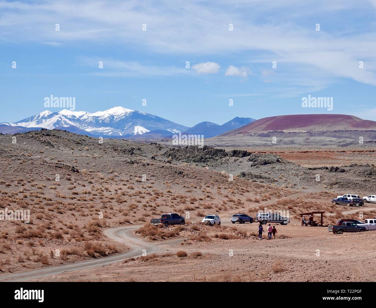 Parked cars and people walking on the Navajo Reservation, NE of Flagstaff, Arizona with snow topped San Francisco peaks in the distance. Stock Photo