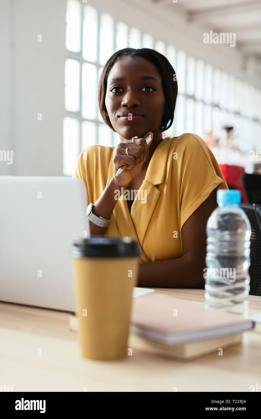 Portrait of confident young woman at desk in office Stock Photo