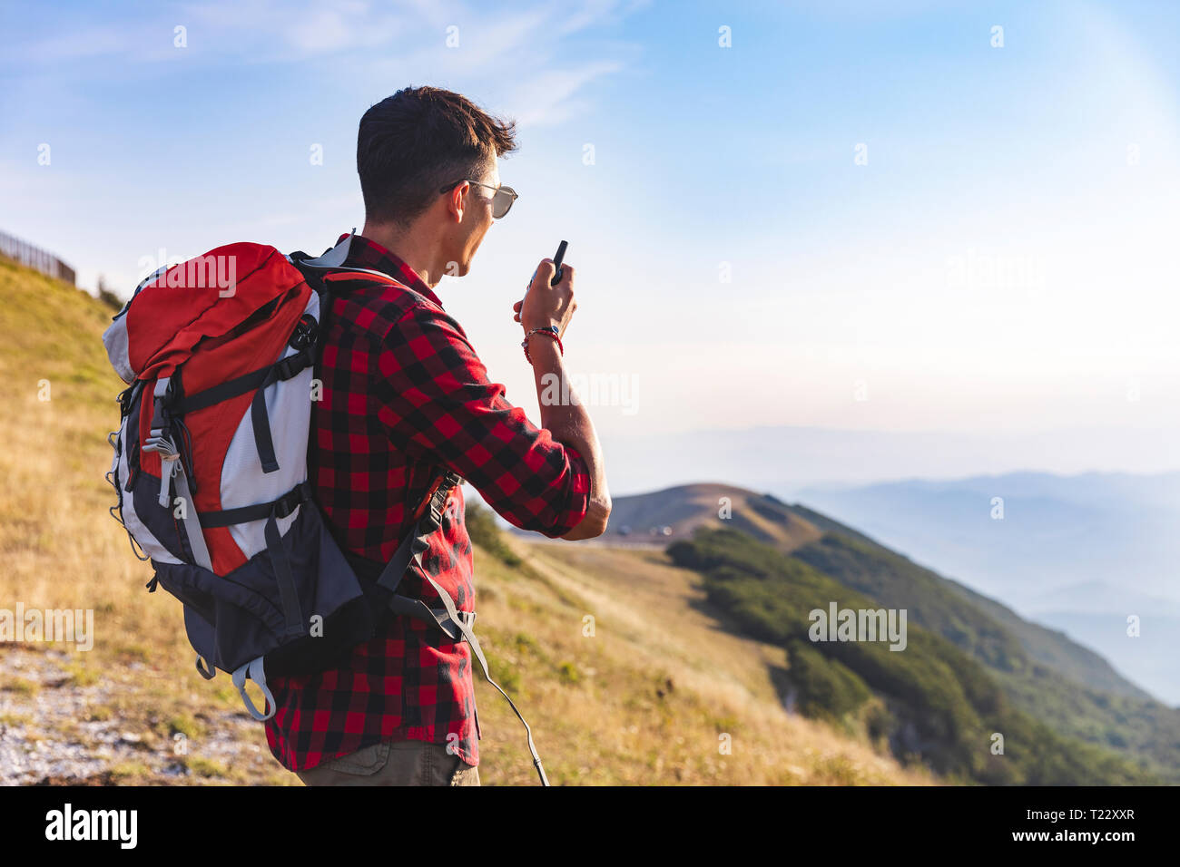 Italy, Monte Nerone, hiker on top of a mountain talking on a walkie talkie Stock Photo