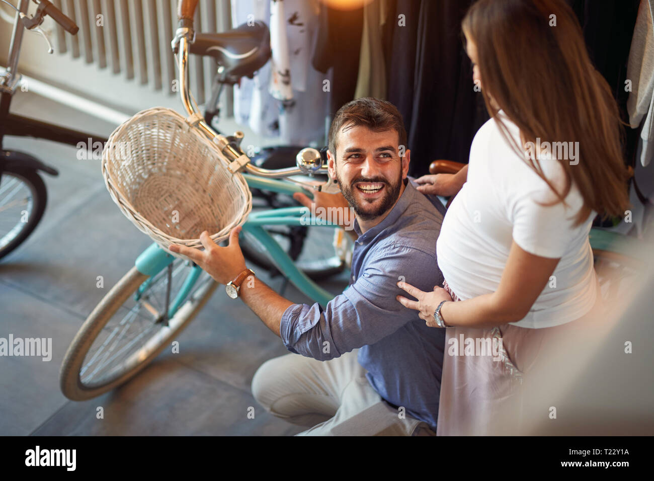 Happy young man shopping new bicycle for his pregnant woman is in bike shop in bike shop Stock Photo
