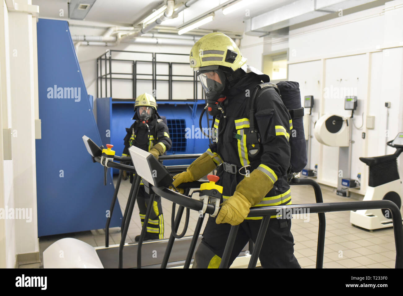 Two firefighters with respirator and air tank exercising in exercise room Stock Photo