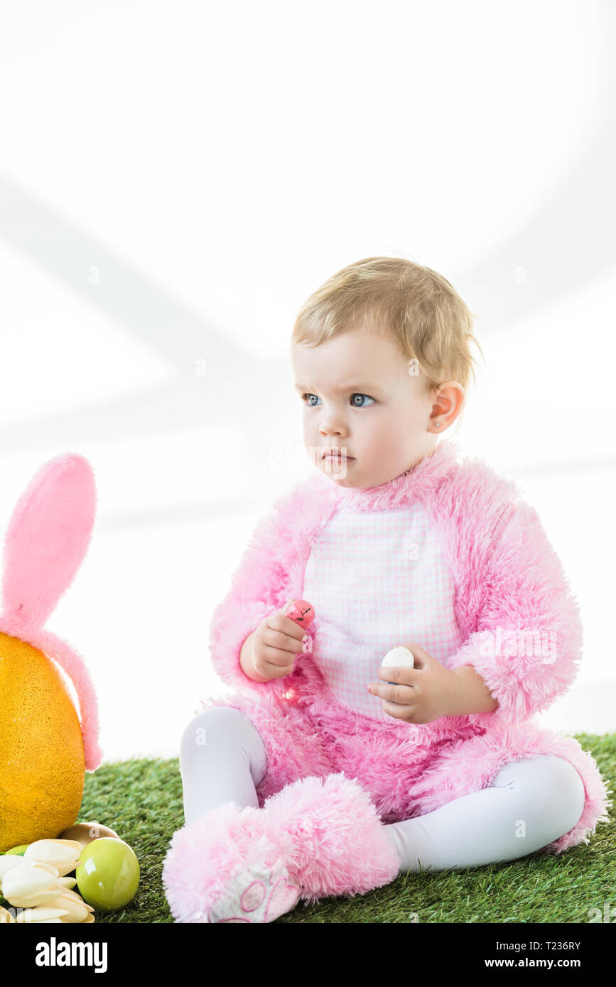 cute kid in pink fluffy costume holding colorful quail eggs isolated on white Stock Photo