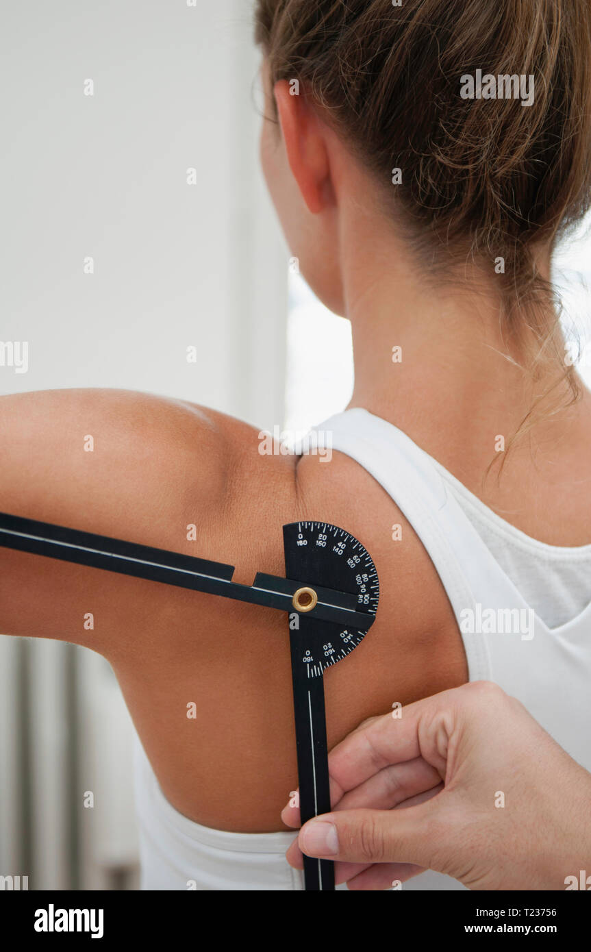 Physiotherapist measure shoulder flexion with goniometer of young female. Stock Photo