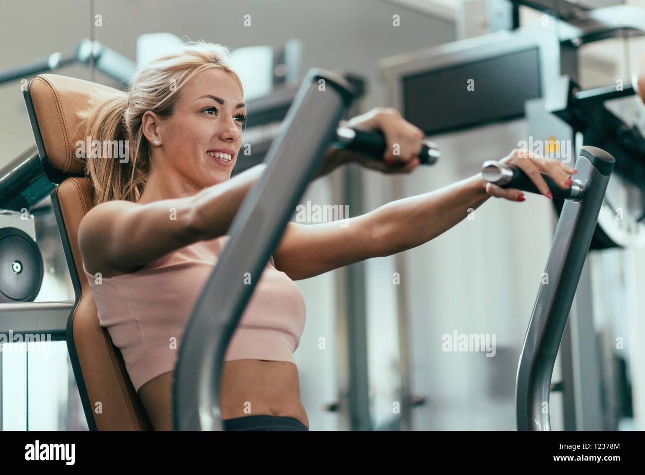 Chest press workout. Young woman exercising in gym Stock Photo - Alamy