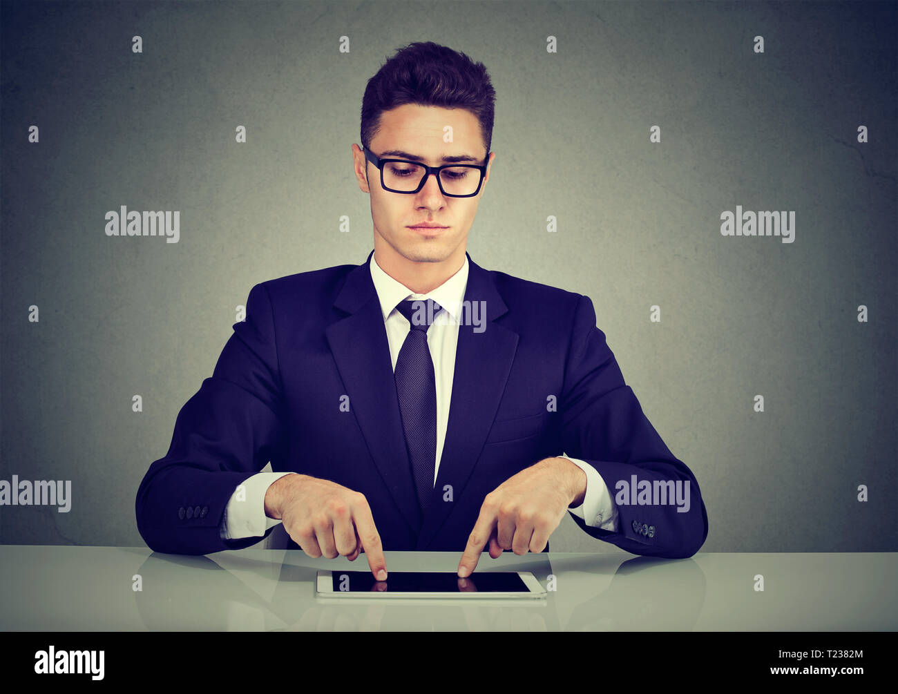 Serious businessman typing with fingers on his tablet computer Stock Photo