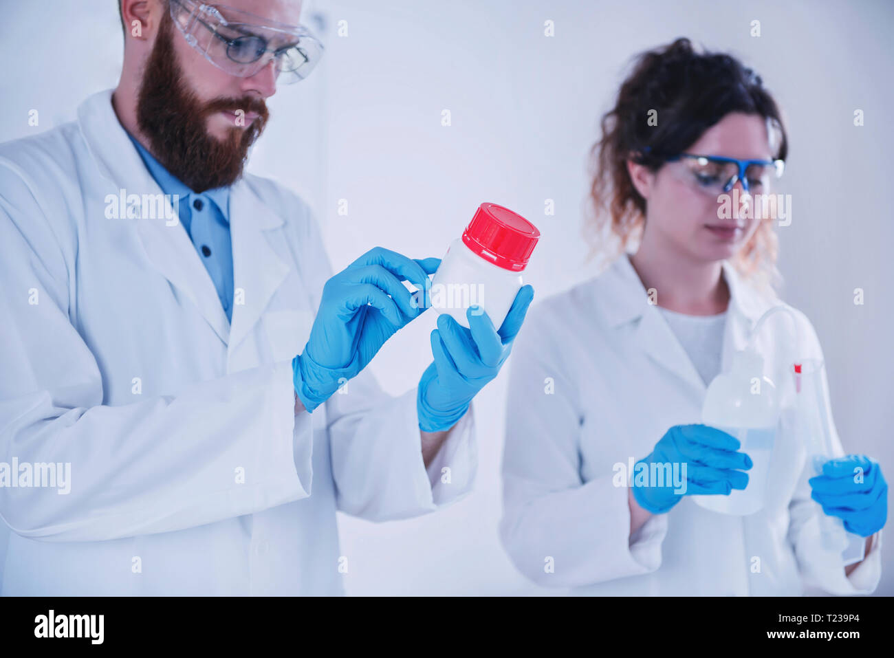 Young researchers working together in the lab, wearing uniform. Stock Photo