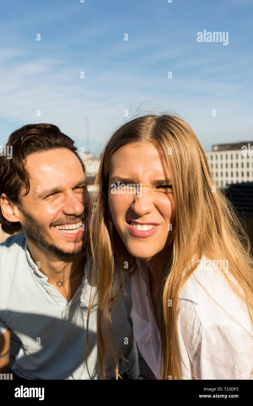 Couple on rooftop terrace, pulling funny faces Stock Photo