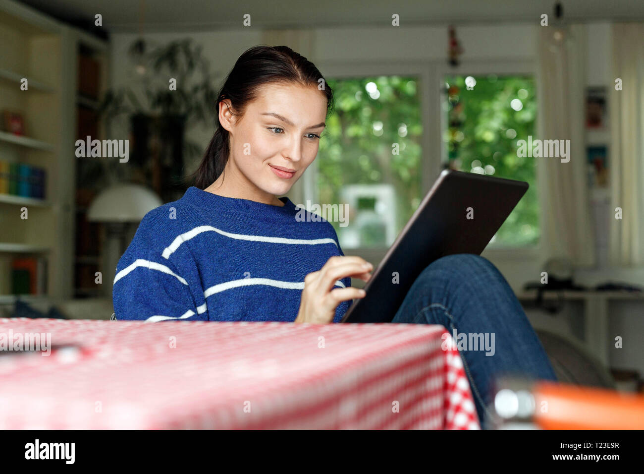 Young woman sitting home tablet hi-res stock photography and images - Alamy