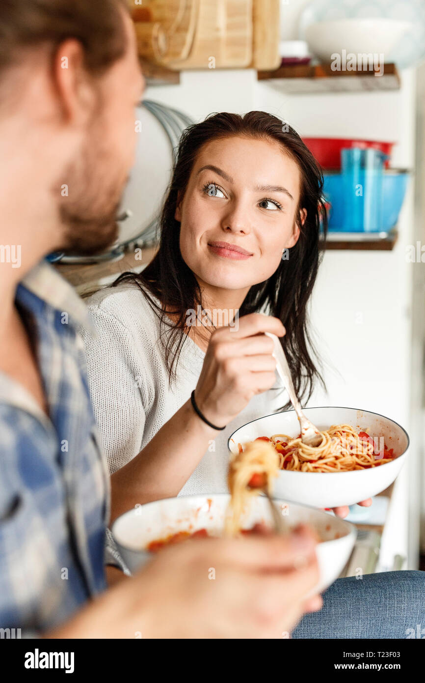 Happy couple sitting in kitchen, eating spaghetti Stock Photo