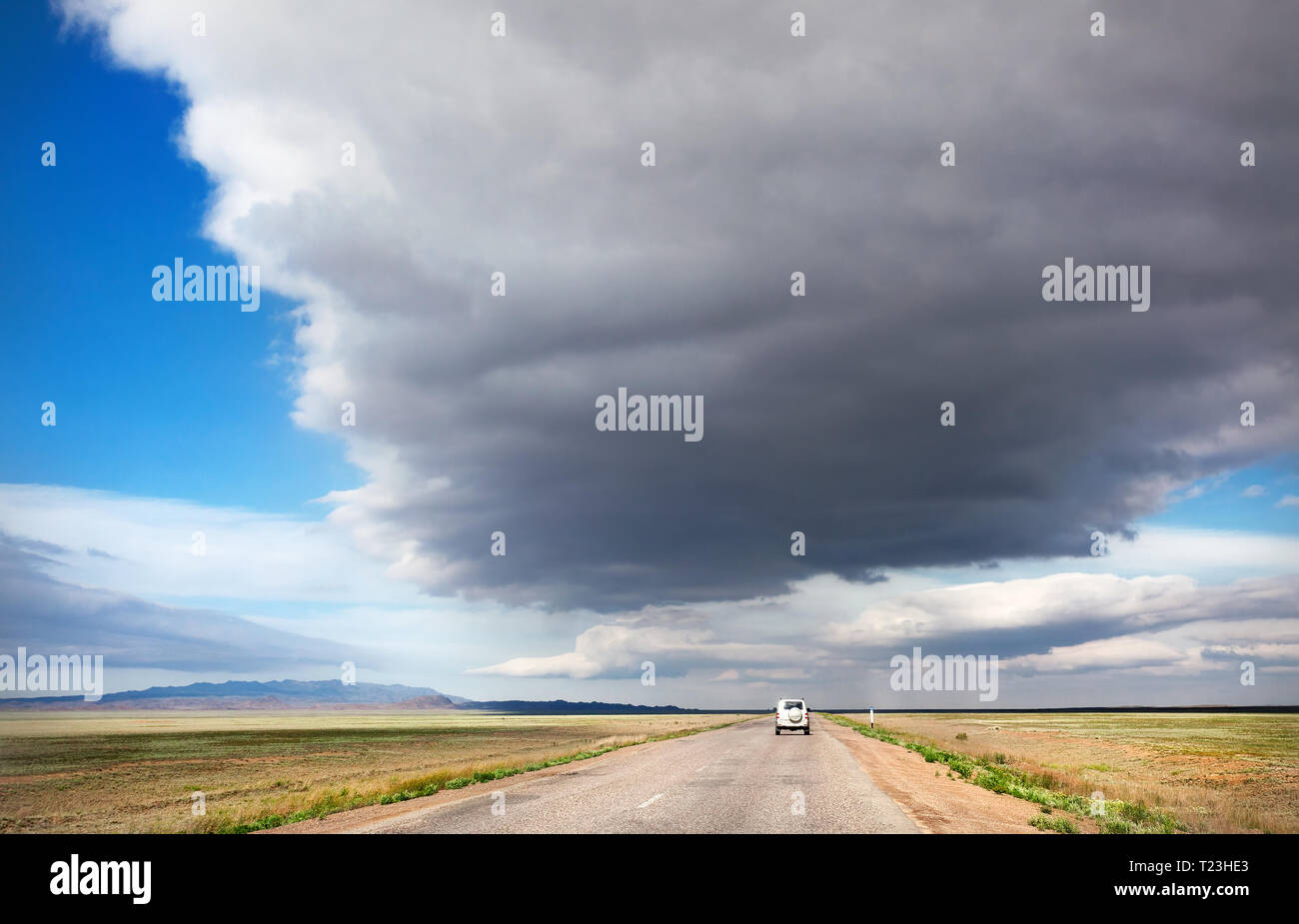 Highway road and lonely car in the desert at overcast sky background Stock Photo