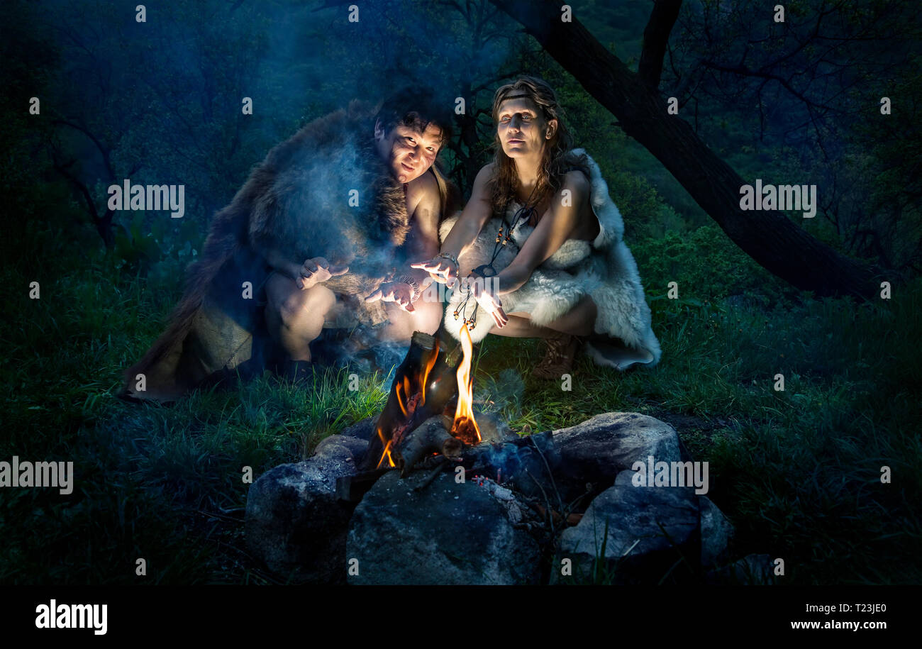 Cave people dressed in animal roast oneself at bonfire in the forest Stock Photo