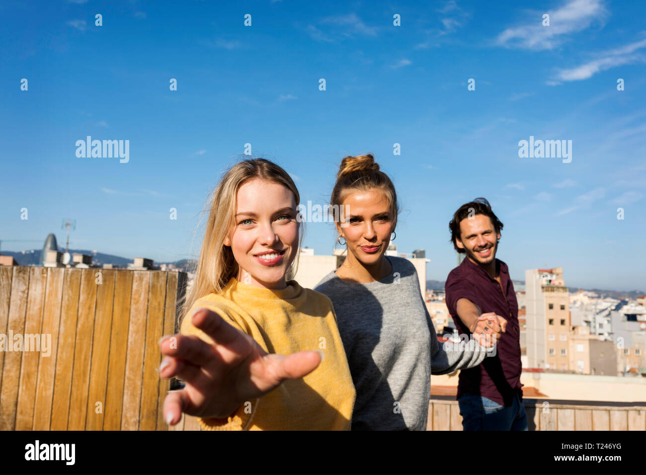 Friends having fun on an urban rooftop terrace, holding hands Stock Photo