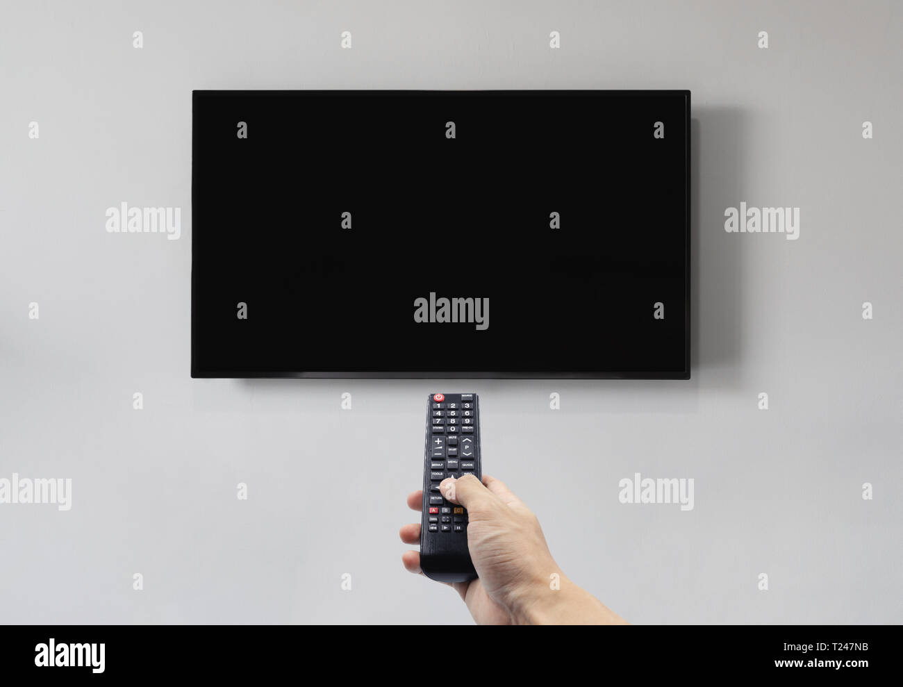 Television on white wall with hand using remote control, blank black ...