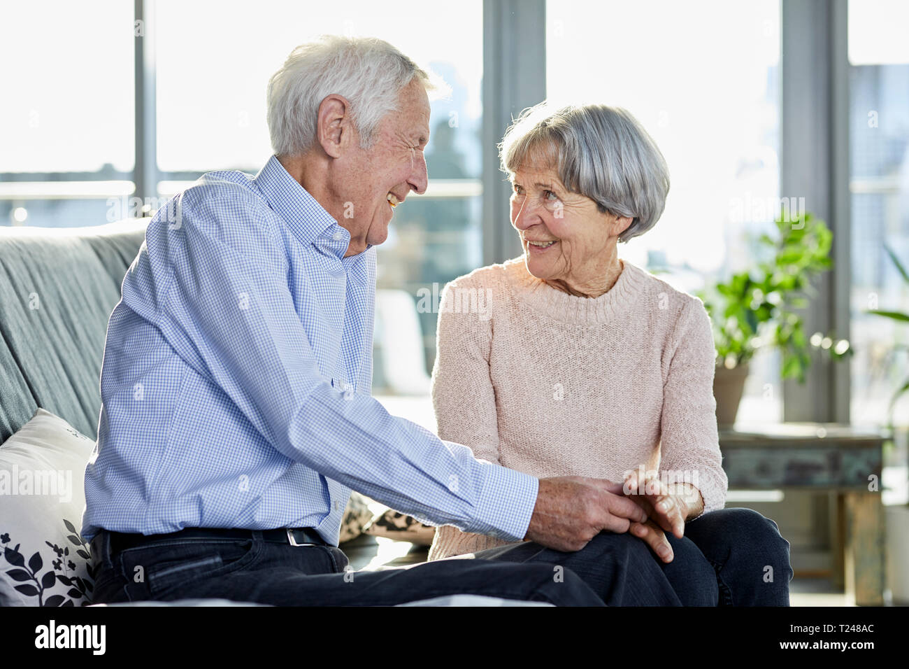 Senior couple sitting on couch talking together Stock Photo
