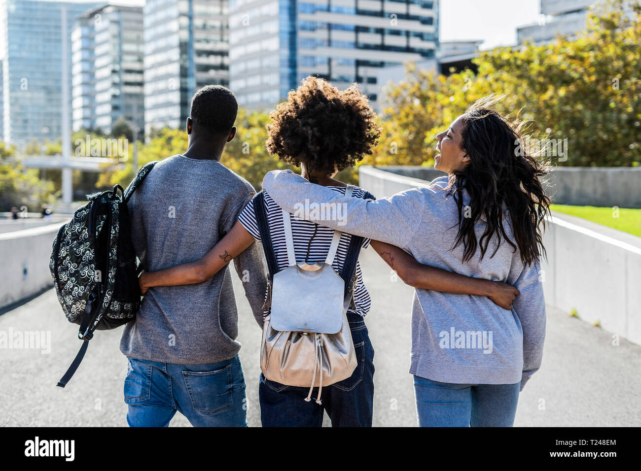 Three friends exploring the city, walking down the street, arm in arm Stock  Photo - Alamy