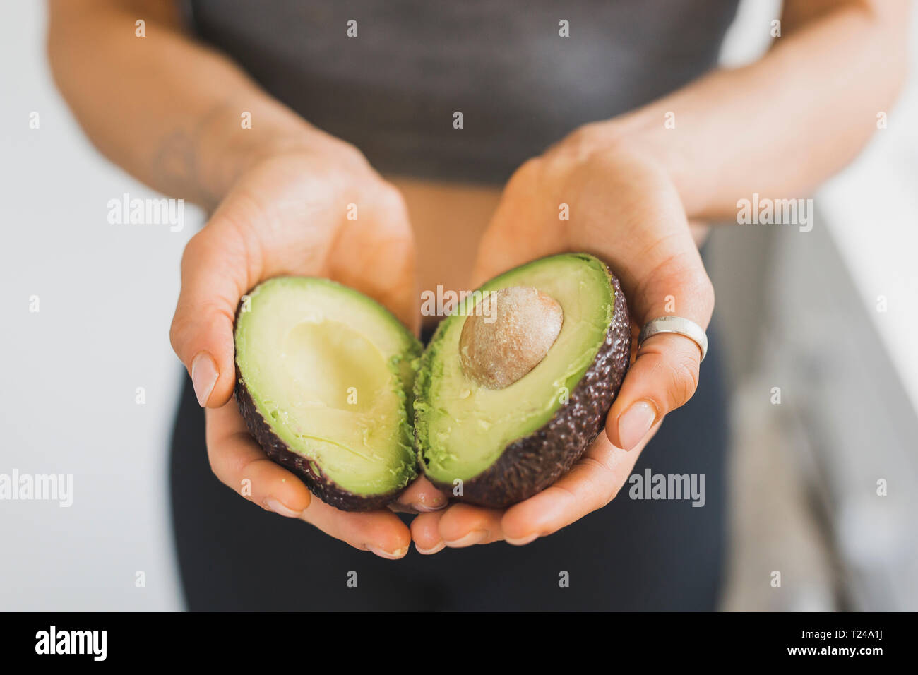 Hands of woman holding halved avocado Stock Photo