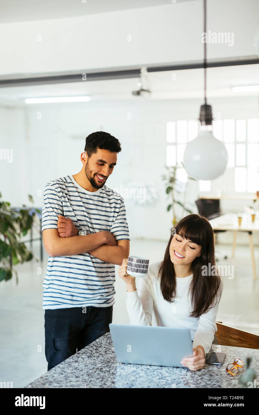 Two smiling colleagues working together at table with laptop Stock Photo