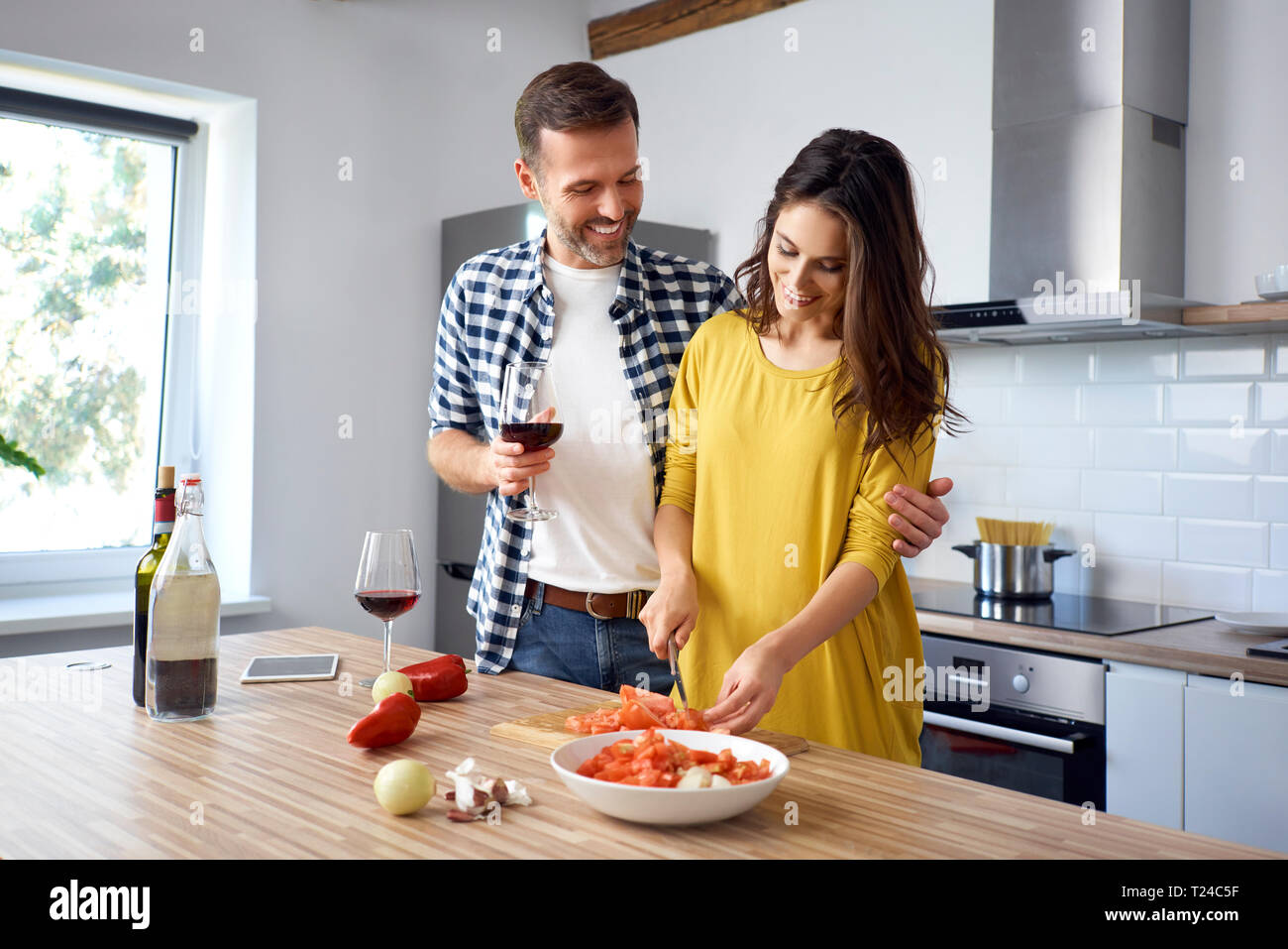 Affectionate couple in kitchen, preparing spaghetti toghether, drinking red wein Stock Photo